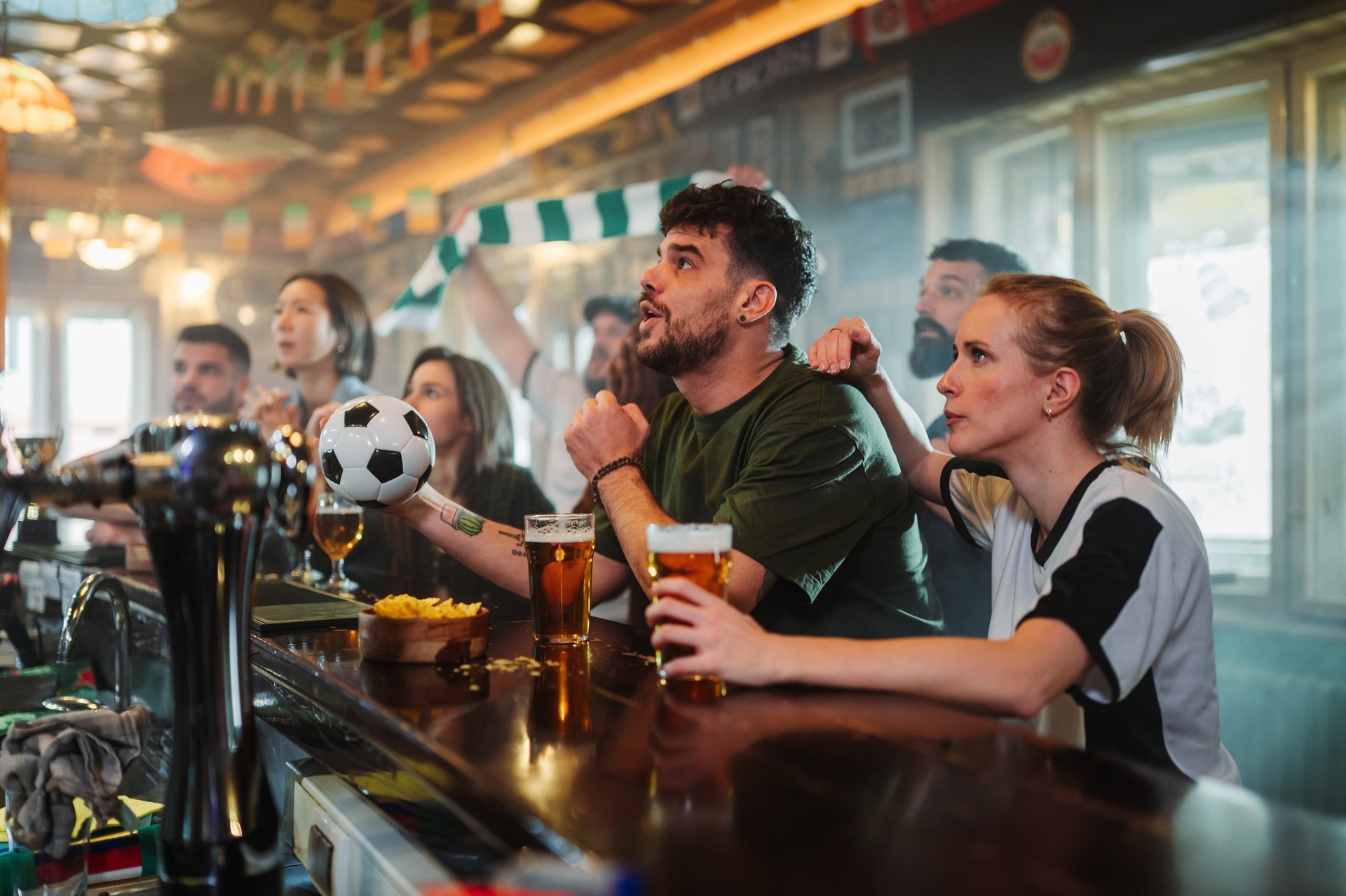 Enthusiastic football supporters gathering in a pub, passionately following a match on tv, expressing joy and disappointment